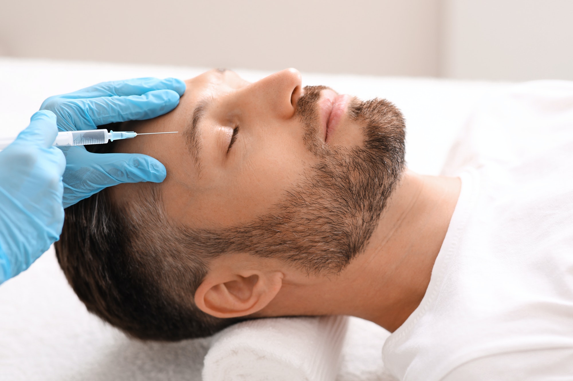 Beautician making face lifting procedures for middle aged man