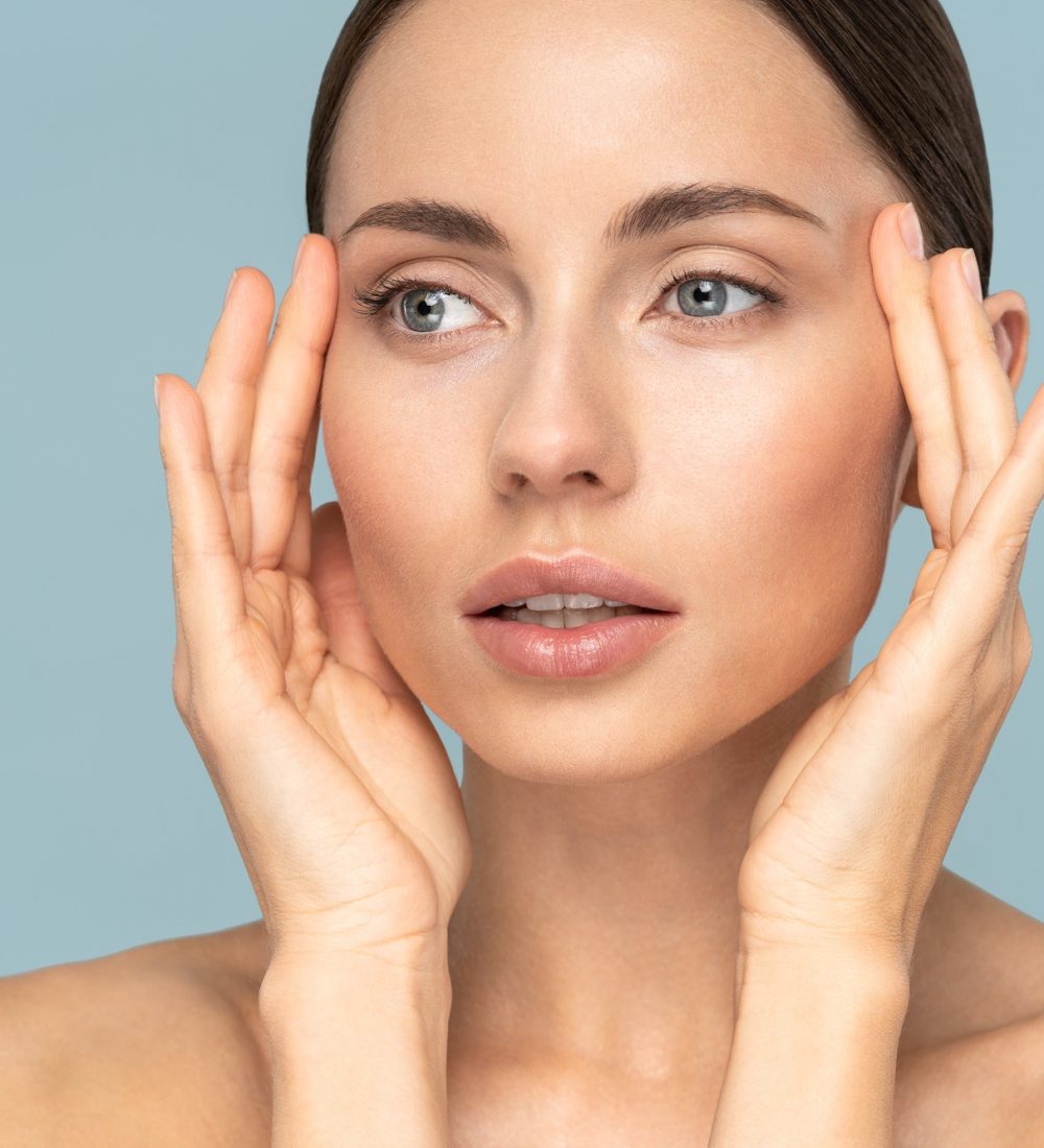 woman with natural makeup, combed hair, touching well-groomed pure skin on face. Beauty, facelift